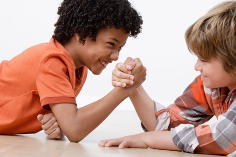 Studio shot of two boys (8-9) arm-wrestling. Photo : Rob Lewine