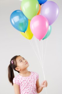 Studio shot of girl (8-9) holding bunch of balloons. Photo : Rob Lewine