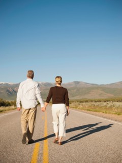 Mid adult couple walking along empty road . Photo: Erik Isakson