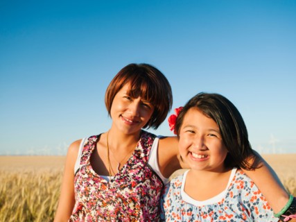 Mother and daughter (10-11) standing in wheat field .