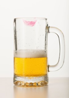 Lipstick on beer glass, studio shot.
