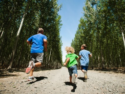 Father with sons (2-9) running up country road.