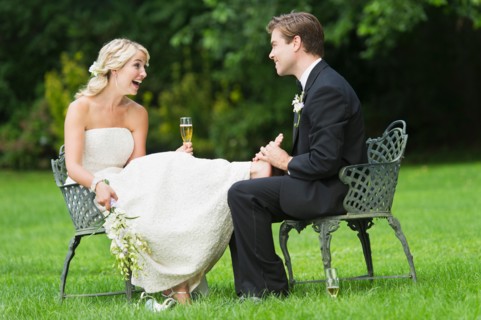 Newly wed couple sitting, groom massaging bride's feet.