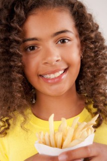 Studio portrait of girl (10-11) holding french fries. Photo: Rob Lewine