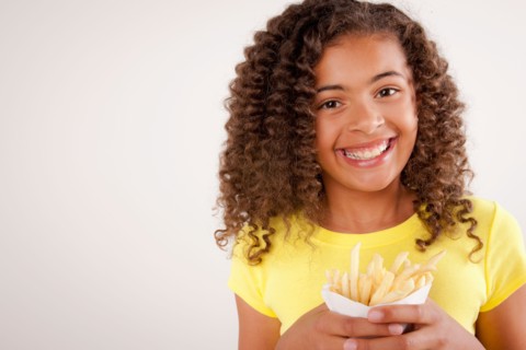 Studio portrait of girl (10-11) holding french fries. Photo: Rob Lewine