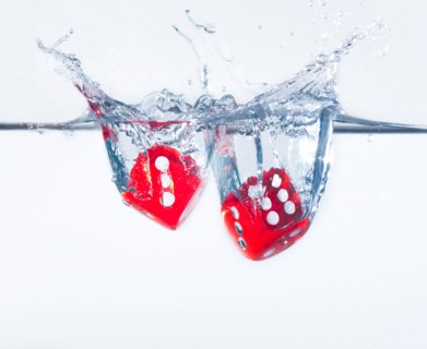 Two dices splashing into water, studio shot. Photo : Daniel Grill