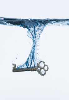 Silver key splashing into water, studio shot. Photo : Daniel Grill