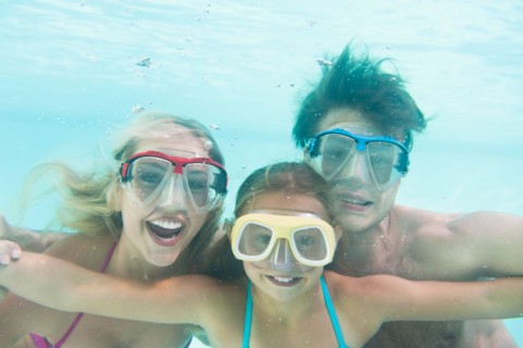Parents with daughter (10-11) swimming underwater. Photo: Daniel Grill