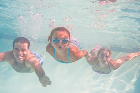 Parents with daughter (10-11) swimming underwater. Photo : Daniel Grill