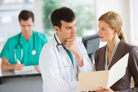 Doctor and businesswoman discussing files.