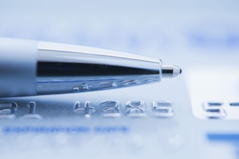 Ballpoint pen on credit card, studio shot.