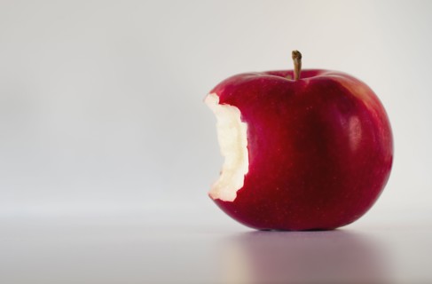 Red apple with missing bite, studio shot.