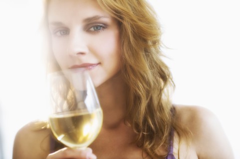 Portrait of young woman smelling wine, studio shot.