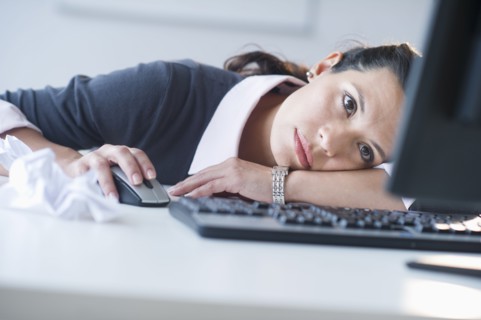 Businesswoman in front of computer, looking tired.