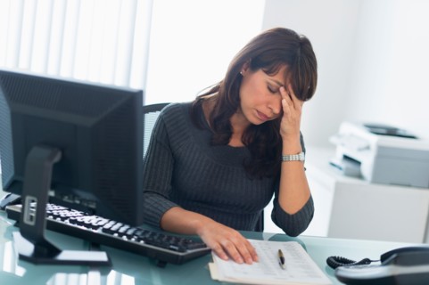 Business woman using computer, looking tired.