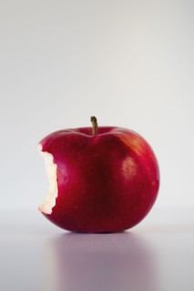 Red apple with missing bite, studio shot.