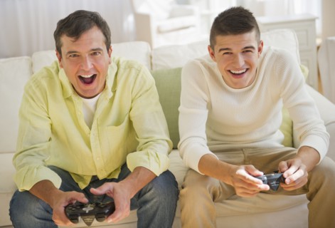 Father and son (16-17) playing video game.