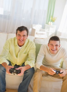 Father and son (16-17) playing video game.