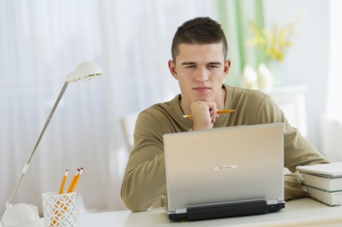 Boy (16-17) using laptop.