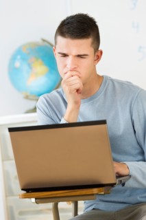 Teenage (16-17) student using laptop.