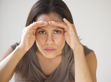 Studio shot of woman shielding eyes.