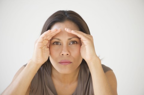 Studio shot of woman shielding eyes.