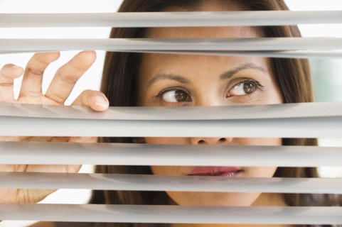 Studio shot of woman looking through blinds.