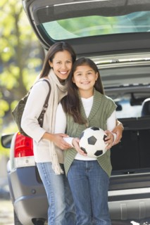 Portrait of mother with daughter (10-11) holding soccer ball.
