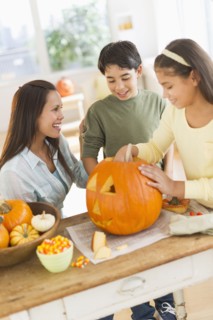 Mother with son (12-13) and daughter (10-11) doing Jack o lantern.