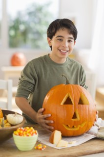 Portrait of boy (12-13) holding Jack o lantern.