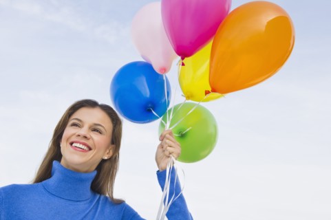 Smiling woman holding balloons.