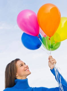 Smiling woman holding balloons.