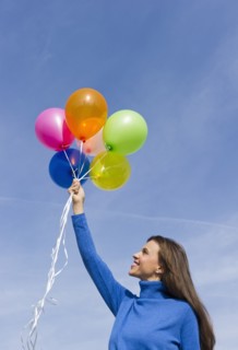 Smiling woman holding balloons.