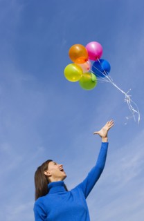 Smiling woman loosing balloons.