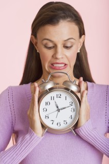 Studio shot of woman holding alarm clock.