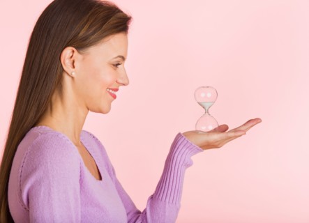 Studio shot of woman holding small hourglass.