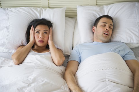 Couple in bed, man snoring.