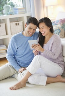 Couple using digital tablet at home.