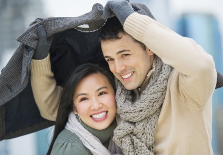 Couple walking with jacket over heads.