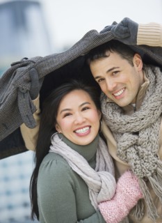 Couple walking with jacket over heads.