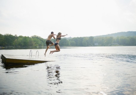 USA, New York, Putnam Valley, Roaring Brook Lake, Couple jumping from pier to lake. Photo: Jamie