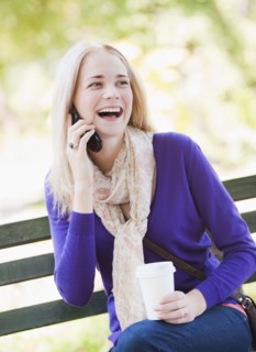 USA, New York, New York City, Manhattan, Central Park, Young woman sitting on bench and talking on