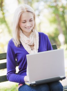 USA, New York, New York City, Manhattan, Central Park, Young woman sitting on bench and using