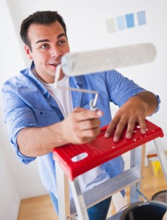 Man standing on ladder with paint roller. Photo : Daniel Grill