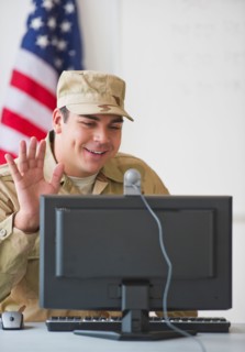 Man wearing military uniform waving to monitor. Photo : Daniel Grill