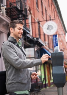 Man inserting coin to parking meter. Photo: Daniel Grill