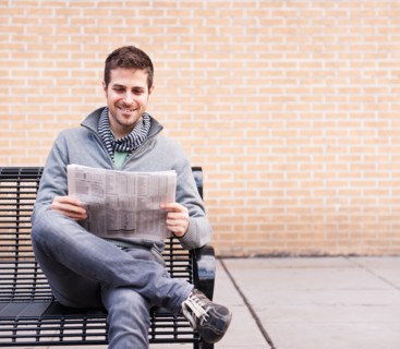 Man on bench reading newspaper. Photo : Daniel Grill