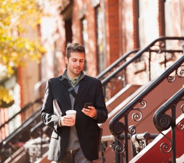 Man walking with mobile phone and coffee. Photo : Daniel Grill