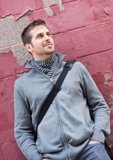 Man standing at front of old peeling red wall. Photo : Daniel Grill