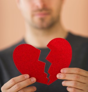 Young man holding broken paper heart. Photo: Daniel Grill